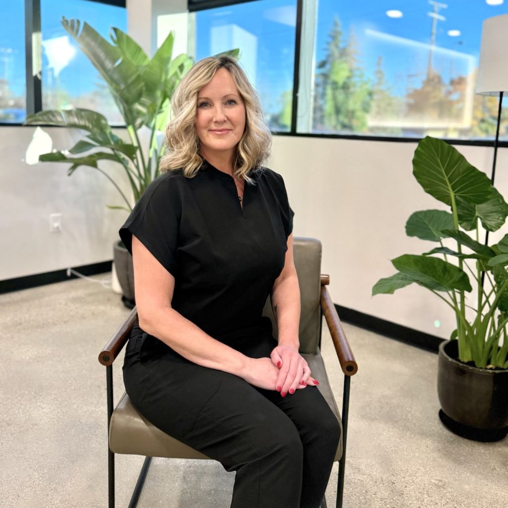 Professional woman in black scrubs sitting in modern office.