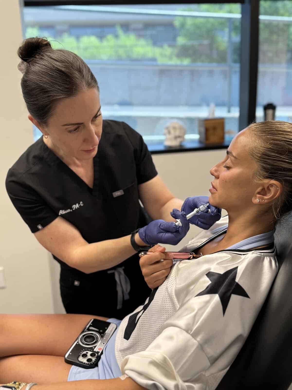 Aesthetic professional administering a cosmetic treatment to a patient.